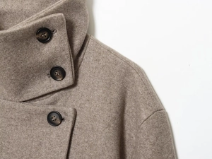 Détail macro du manteau en laine beige avec col montant et boutons en écaille bruns