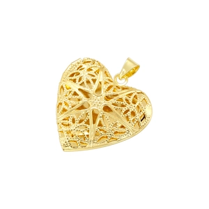 Détail d'un pendentif cœur doré vintage aux motifs d'étoiles et de fleurs ajourés