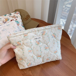 Detailed macro shot of the quilted cotton pouch with floral patterns and logo tag