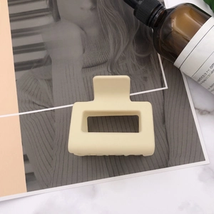 Close-up of a matte beige square hair claw clip on a minimalist lifestyle background