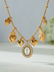 Detail of vintage gold necklace with heart charms and a sparkling religious medal pendant