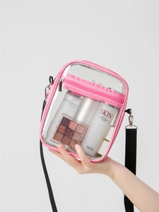 Detail of pink-trimmed transparent PVC crossbody bag showing internal storage and makeup
