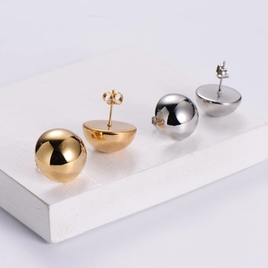 Elegant minimalist gold and silver hemisphere stud earrings on white wooden display