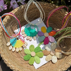 Detailed view of handmade colorful raffia flower and shell pendants in straw basket