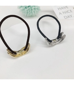Detail of U-shaped gold and silver metal pony cuff hair ties on a textured tray