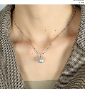 Detail shot of a silver snake chain necklace featuring a single radiant grey pearl pendant