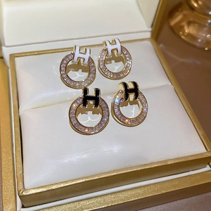 Close-up of luxury gold-plated H-shaped earrings with white and black zircon crystals