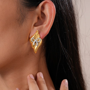 Gros plan de boucles d'oreilles nœud géométrique avec finition or et argent texturée
