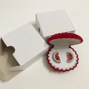 Detail of watermelon stud earrings with rhinestones inside a red shell velvet jewelry box