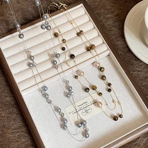 Detail of tiger eye and pearl beaded necklaces on a vintage wooden jewelry display tray