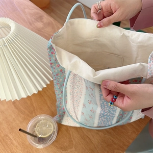 Détail d'un sac cabas fleuri montrant l'intérieur spacieux avec poche zippée et doublure