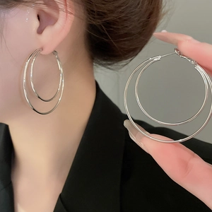 Close-up of double layered silver hoop earrings worn to show the minimalist metallic texture