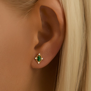 Close-up of gold flower cartilage stud featuring a green zircon and white gems