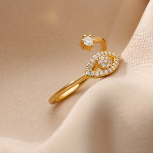 Close-up of golden evil eye ring with micro-paved zircons on champagne silk background