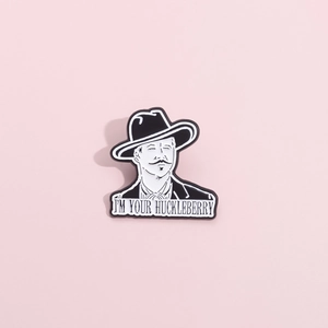Detail of the black and white enamel pin featuring the text I'M YOUR HUCKLEBERRY