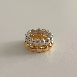 Close-up of stacked minimalist 925 sterling silver beaded rings in gold and silver finish