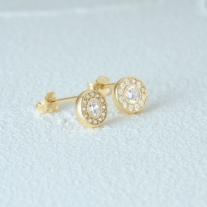 Macro shot of gold floral earrings featuring a central round zircon and halo detail