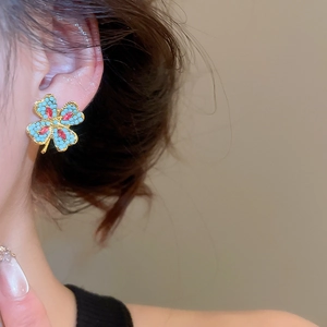 Close-up of vintage flower stud earrings with turquoise beads and red crystal details