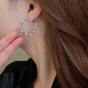 Side view detail of a silver irregular geometric earring worn on model's ear