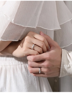 Close-up of S925 silver couple rings with zircon insets on hands in a romantic setting