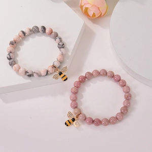 Detail of pink agate beads bracelet with a gold bee charm and zircon stones