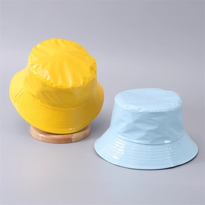 Dettaglio di cappelli alla pescatora in pelle PU lucida gialla e blu con tesa cucita