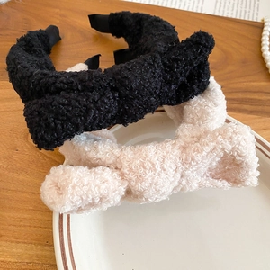 Detail of plush bow headbands in black and cream beige on a ceramic plate