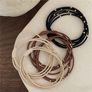 Detailed close-up of elastic hair bands with golden beads on a matte ceramic plate