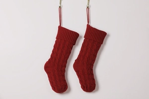 Close-up of red knitted Christmas stockings with classic cable pattern on a white wall