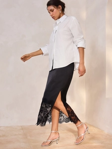Close-up of black satin skirt featuring delicate lace patchwork hem detailing