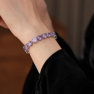 Detail of luxury silver bracelet with round purple cubic zirconia on model's wrist