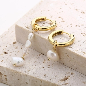Détail de boucles d'oreilles asymétriques en perles baroques avec plaqué or 18 carats