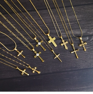 Various 18K gold plated titanium cross pendants with zircon on a dark wood background