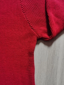 Vista macro dettagliata del tessuto a maglia rosso e della cucitura della manica del maglione