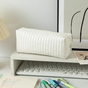 Close-up of cream white quilted pencil case with soft texture and smooth top zipper