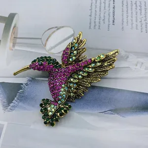 Macro shot of hummingbird brooch featuring colorful rhinestones on a magazine surface