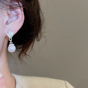 Close-up of elegant silver flower earrings with pearl inlay worn by a female model
