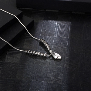 Silver stainless steel snake chain necklace with beads and a heart pendant on black background