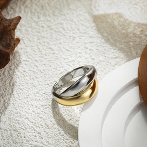 Detailed view of dual-tone 18K gold and silver wide band ring on textured stone base