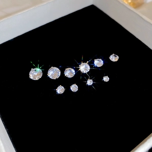 Set of sparkling zircon stud earrings in various sizes arranged on black velvet padding