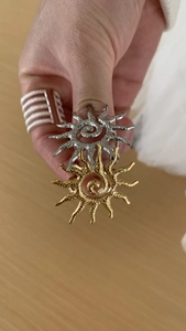 Detailed view of sun-shaped open rings with hammered texture in gold and silver finish