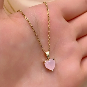 Detail of a pink heart-shaped zircon pendant on a minimalist gold-plated chain necklace
