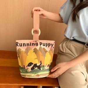 Canvas bucket bag with puppy print and round wooden handles shown in a lifestyle setting
