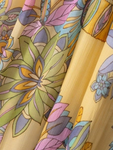 Dettaglio della stampa floreale bohémien gialla su tessuto in chiffon leggero e traslucido