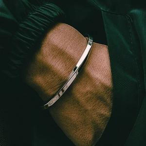 Close-up of a double-layered stainless steel cross chain bracelet on a wrist