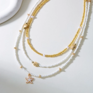 Collier multicouche avec pendentifs étoile de mer et coquillage en perles dorées