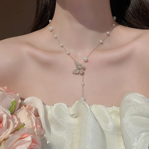 Detail of butterfly pendant pearl necklace with gold chain on model neck