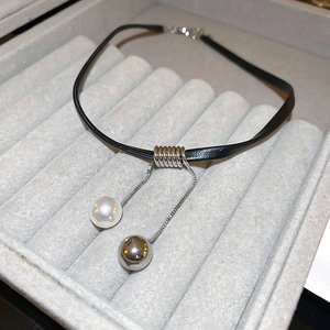 Detail of minimalist black choker with silver metal coils and hanging pearl charms