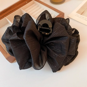 Détail d'une grande pince à cheveux en mesh noir avec reflets argentés et ressort en métal