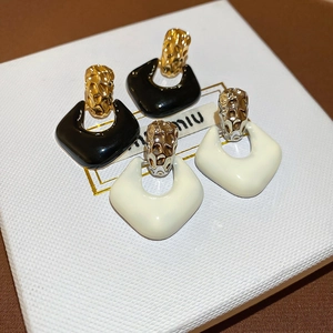 Detailed macro view of vintage geometric drop earrings on a white leather jewelry box
